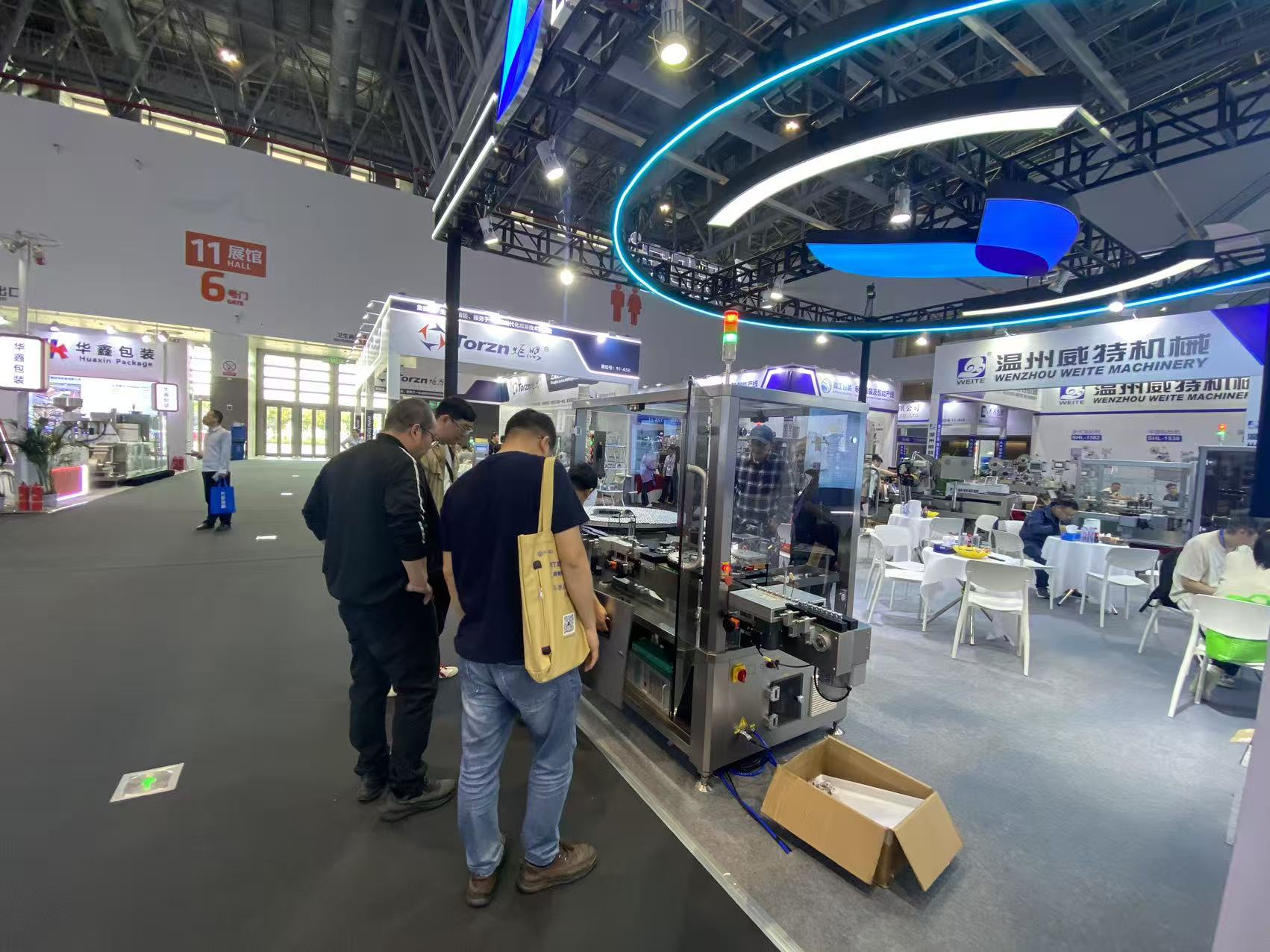 Visitors looking closely at a guarded pharmaceutical labeling machine at the LEBONING booth