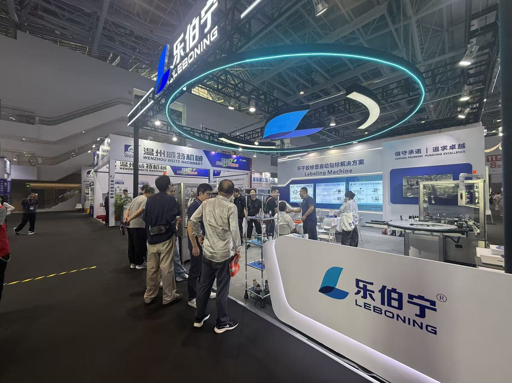 View from the exhibition aisle toward the LEBONING reception counter and labeling machines